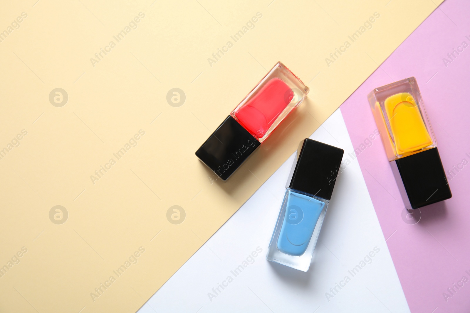 Photo of Bottles of nail polish on color background, top view with space for text