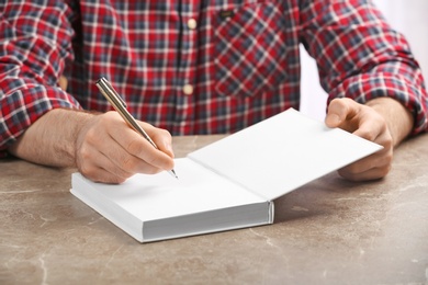 Writer signing autograph in book at table, closeup