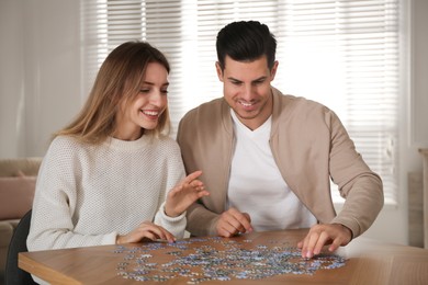 Happy couple playing with puzzles at home