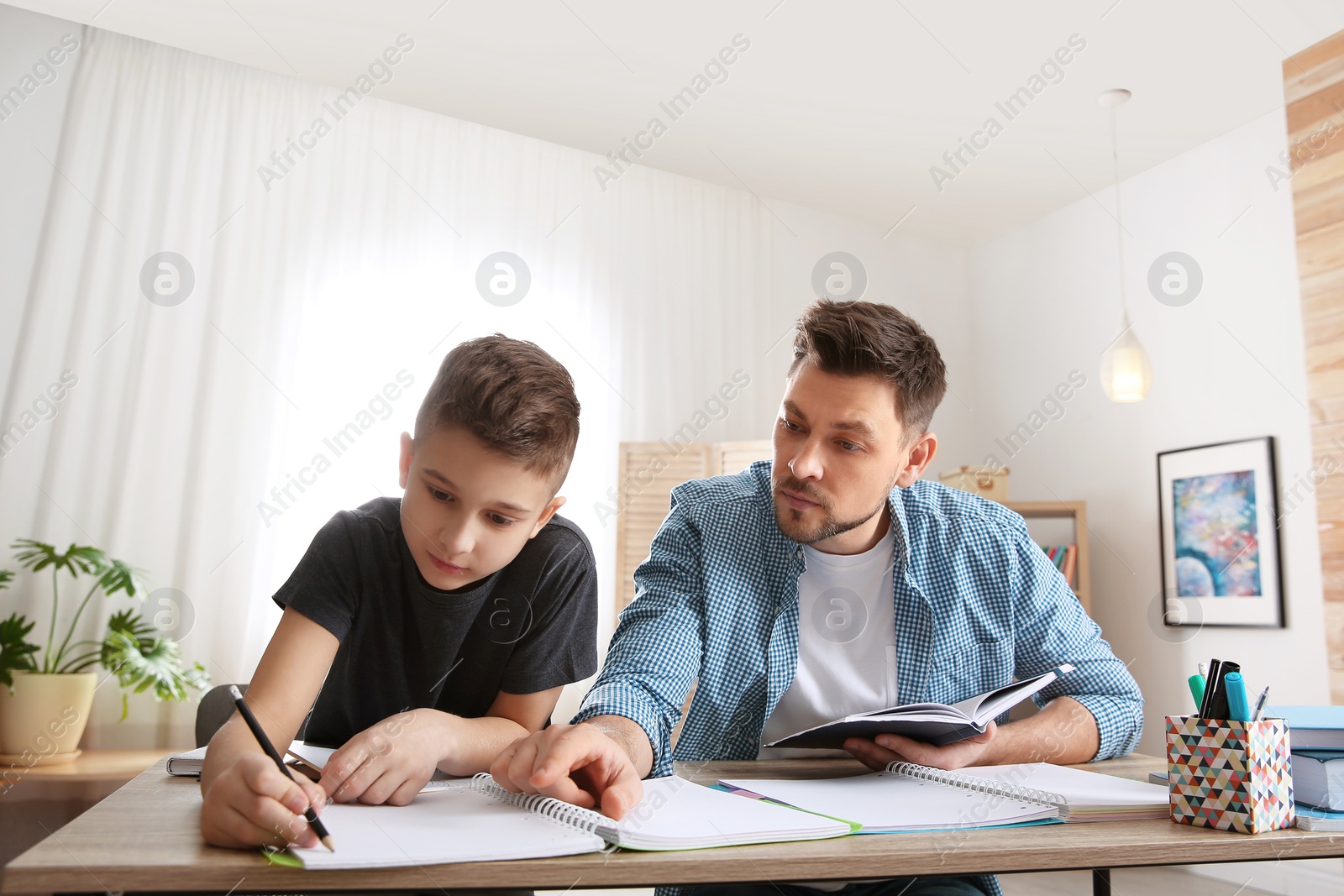 Photo of Dad helping his son with homework in room