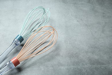 Photo of Two whisks on gray table, space for text