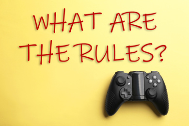 Modern video game controller with text WHAT ARE THE RULES on yellow background, top view