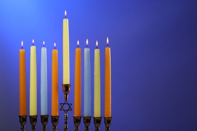 Hanukkah celebration. Menorah with burning candles on blue background, space for text