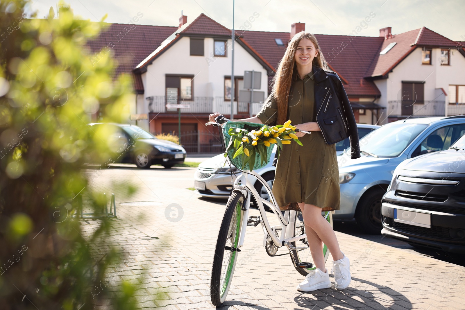 Photo of Beautiful teenage girl with bicycle and bouquet of yellow tulips outdoors on sunny day