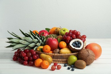 Photo of Wicker tray with different fresh fruits on white wooden table