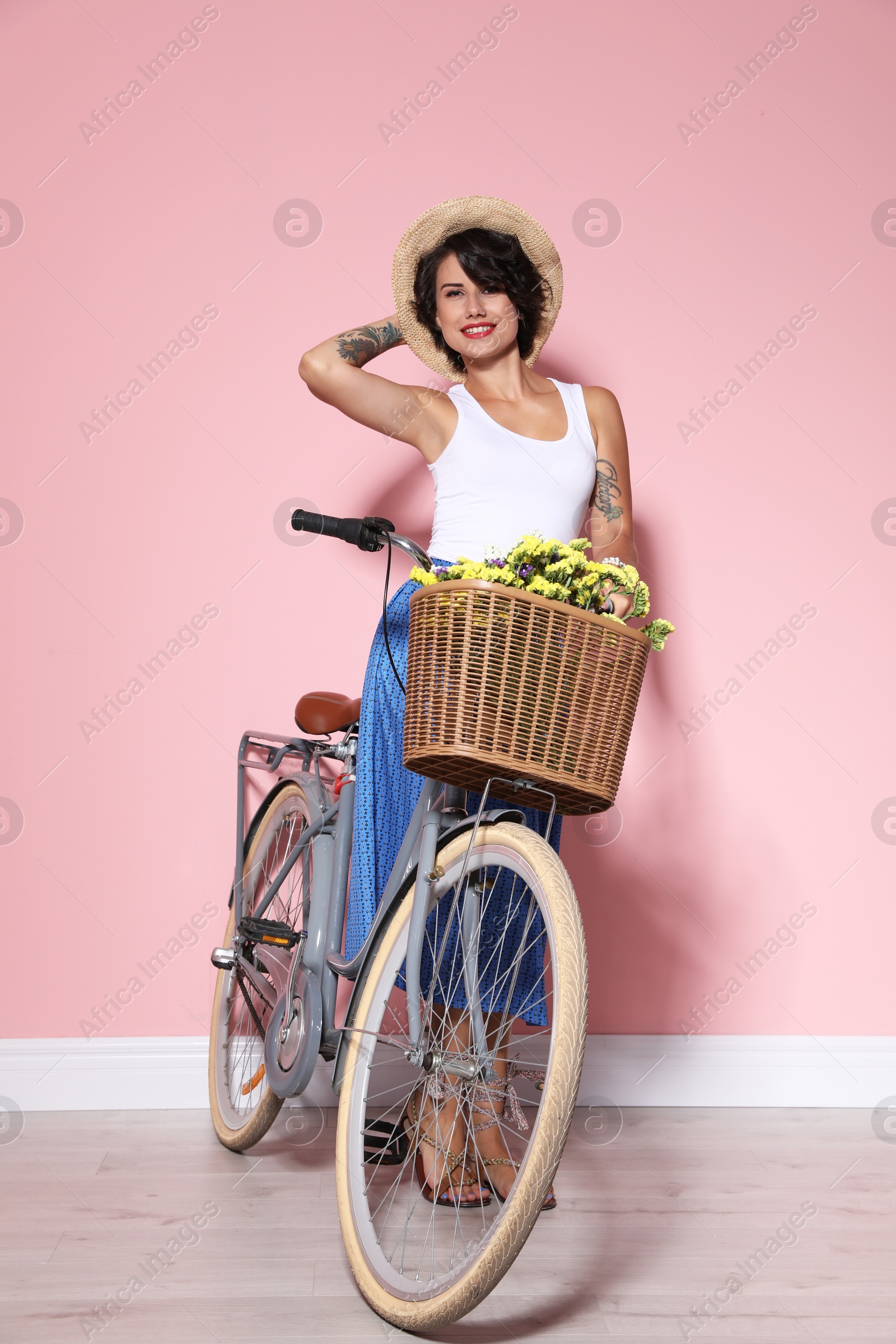 Photo of Portrait of beautiful young woman with bicycle near color wall