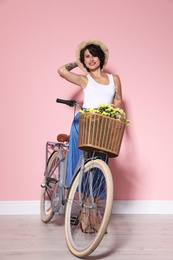 Portrait of beautiful young woman with bicycle near color wall