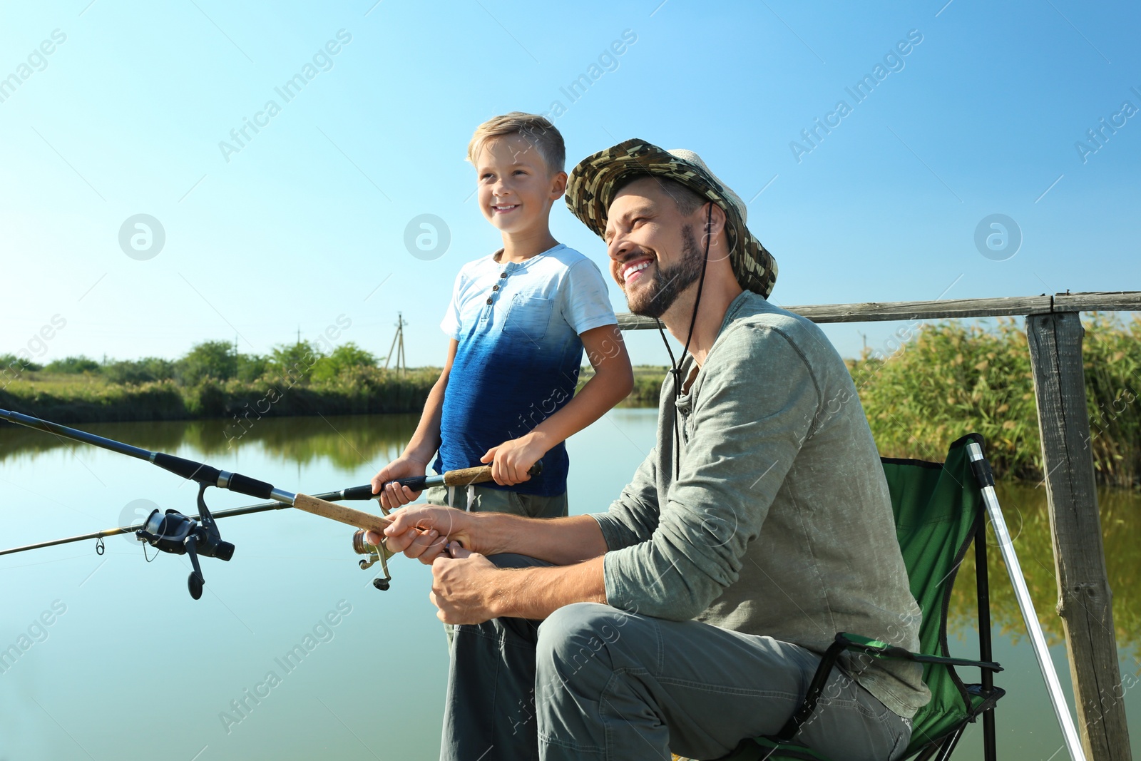 Photo of Father and son fishing together on sunny day