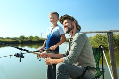 Father and son fishing together on sunny day