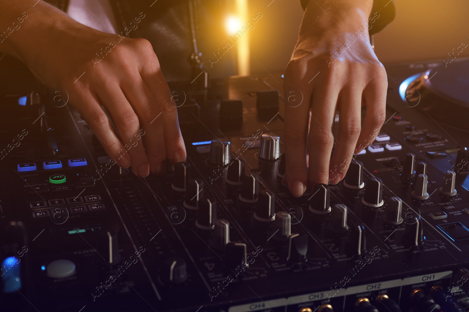 Photo of DJ creating music on modern console mixer in night club, closeup