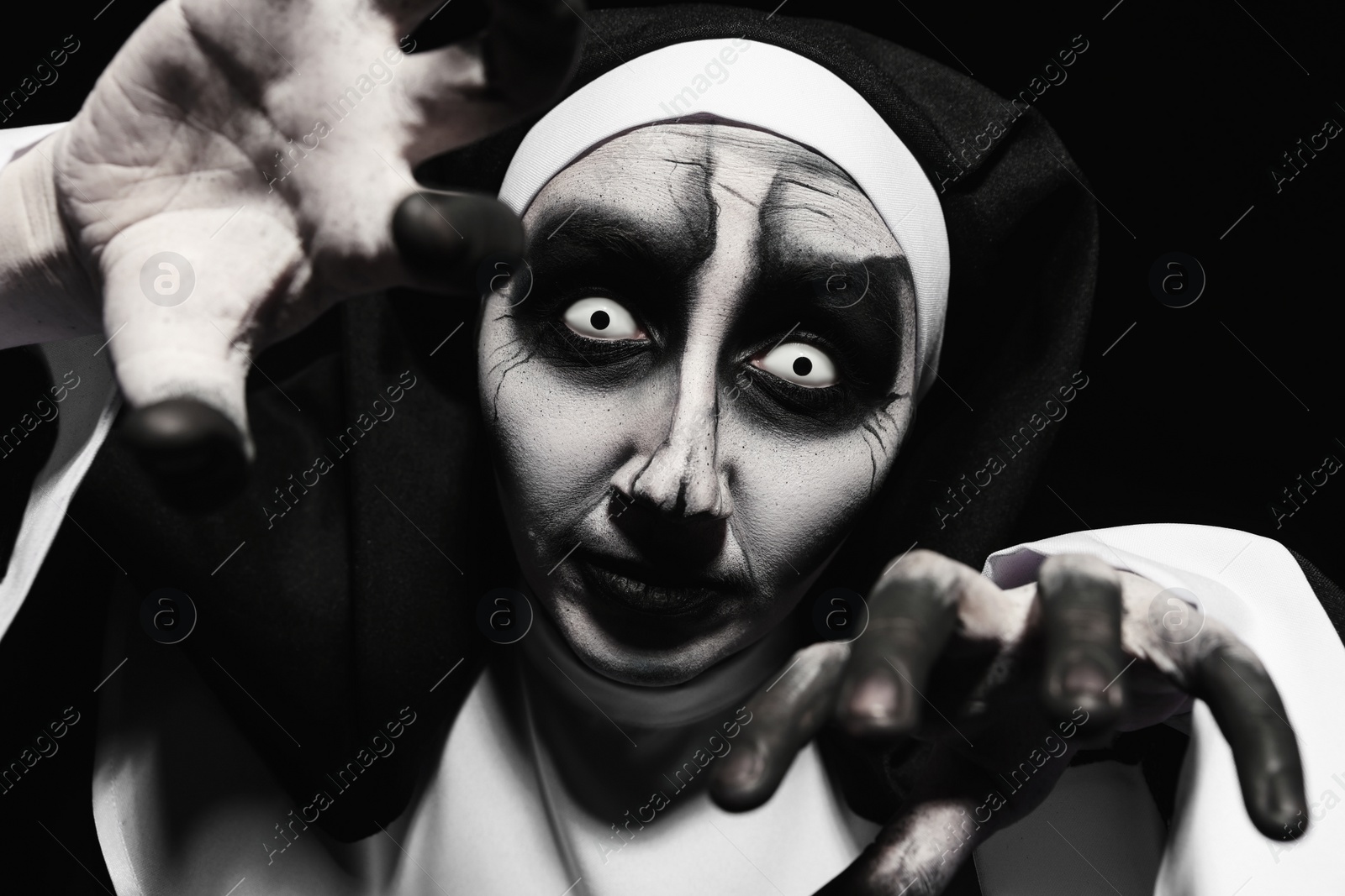 Photo of Scary devilish nun frightening on black background. Halloween party look