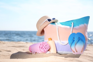 Photo of Bag and beach objects on sand near sea, space for text