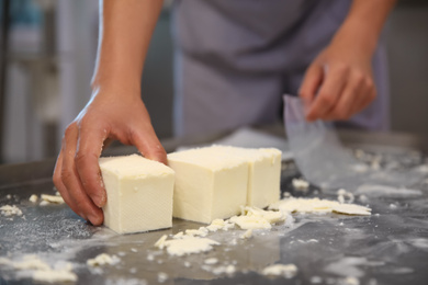 Worker packaging feta cheese at modern factory, closeup