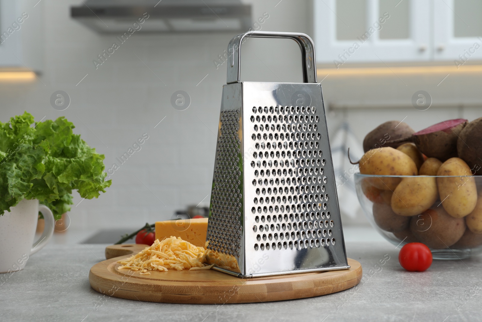 Photo of Grater, cheese and vegetables on table in kitchen