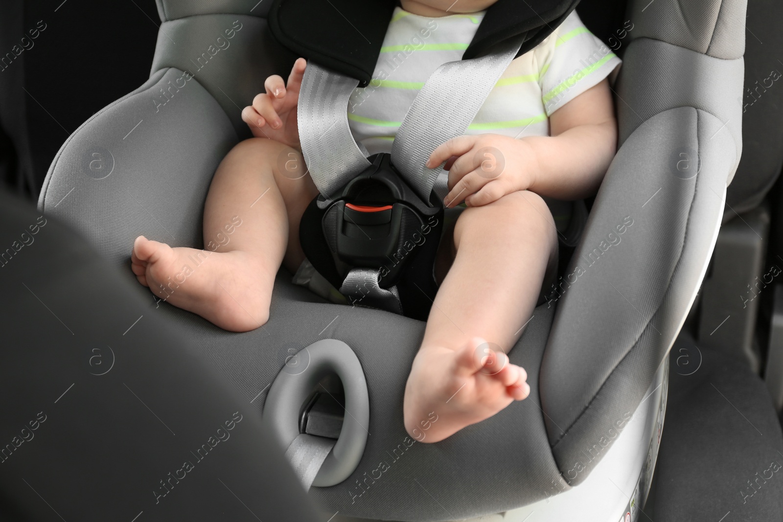 Photo of Little baby in child safety seat inside of car, closeup on legs