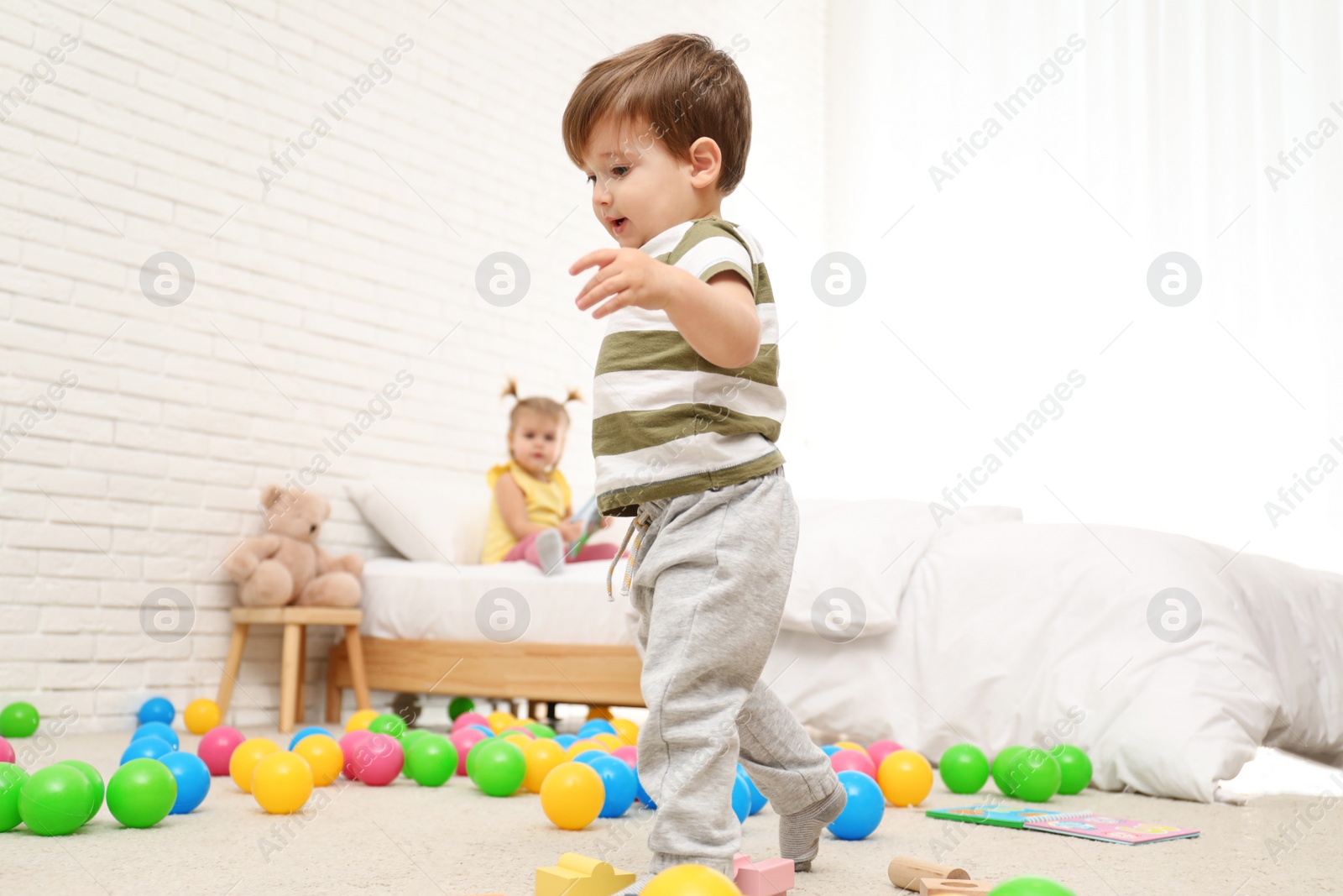 Photo of Cute little child playing with toys on floor at home