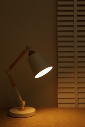 Photo of Stylish modern desk lamp on table at night