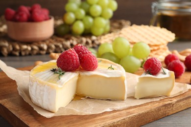 Photo of Brie cheese served with berries on table, closeup