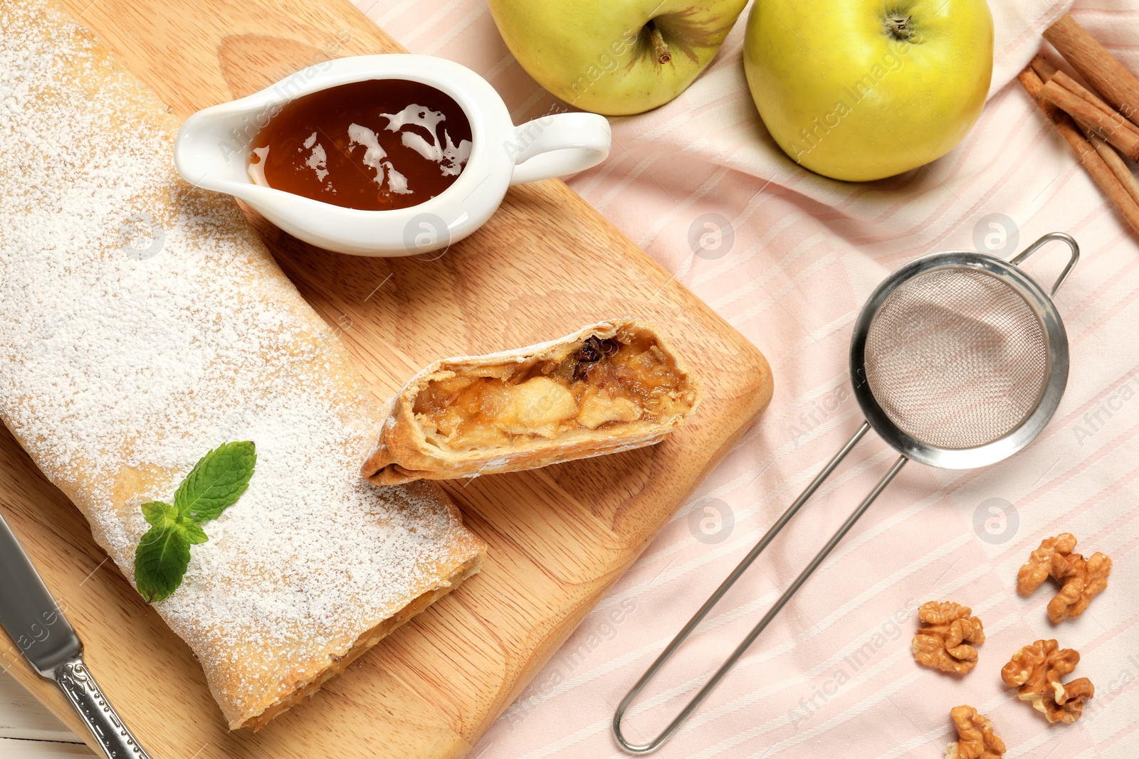 Photo of Delicious strudel with with apples and nuts served on table, flat lay