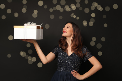 Beautiful woman with Christmas gift on black background