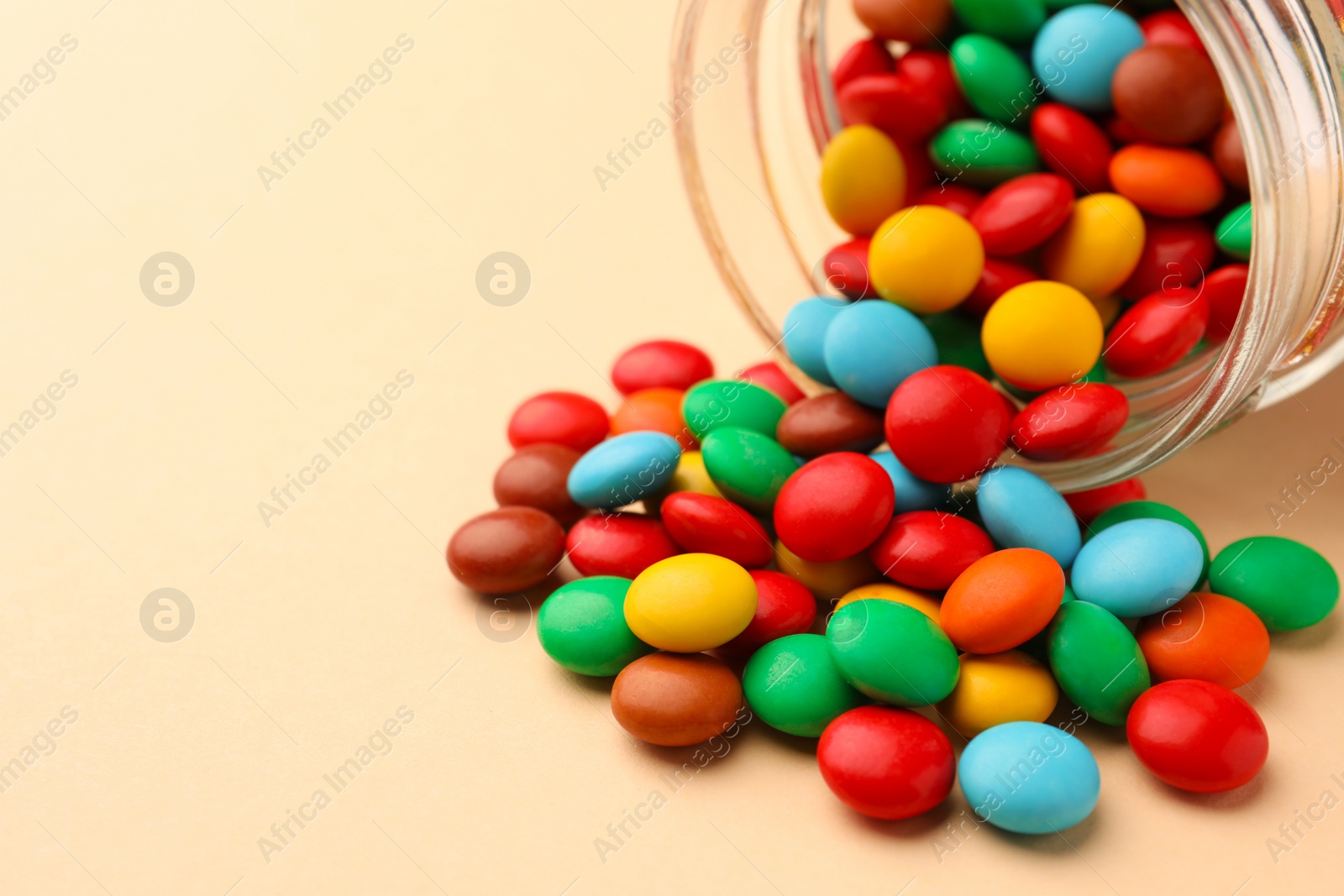 Photo of Tasty colorful candies on beige background, closeup. Space for text