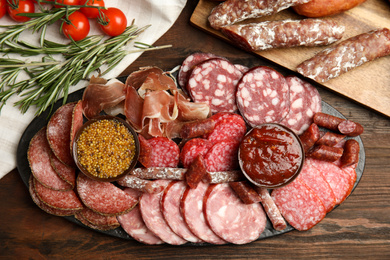 Different types of sausages with sauce served on wooden table, flat lay