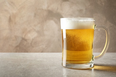 Glass mug with cold tasty beer on table