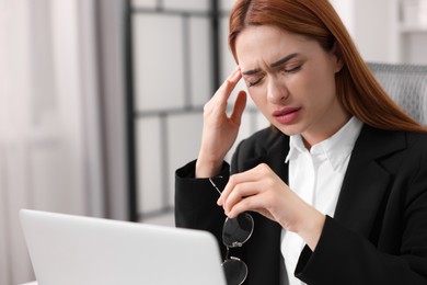 Photo of Woman suffering from headache at workplace in office