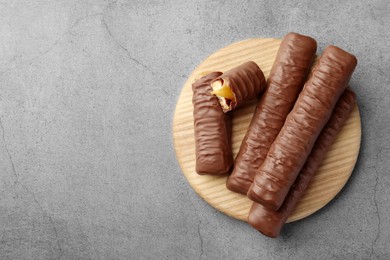 Photo of Sweet tasty chocolate bars with caramel on grey table, top view. Space for text