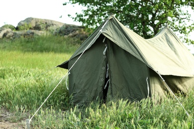 Camping tent in green field on sunny day. Space for text