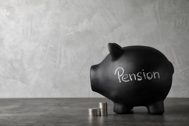 Photo of Piggy bank with word PENSION and coins on table. Space for text