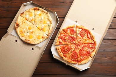 Hot cheese pizzas in cardboard boxes on wooden table, top view. Food delivery service