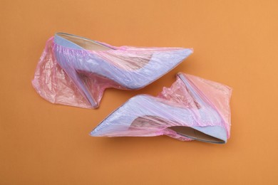 Photo of High heels in shoe covers on brown background, top view