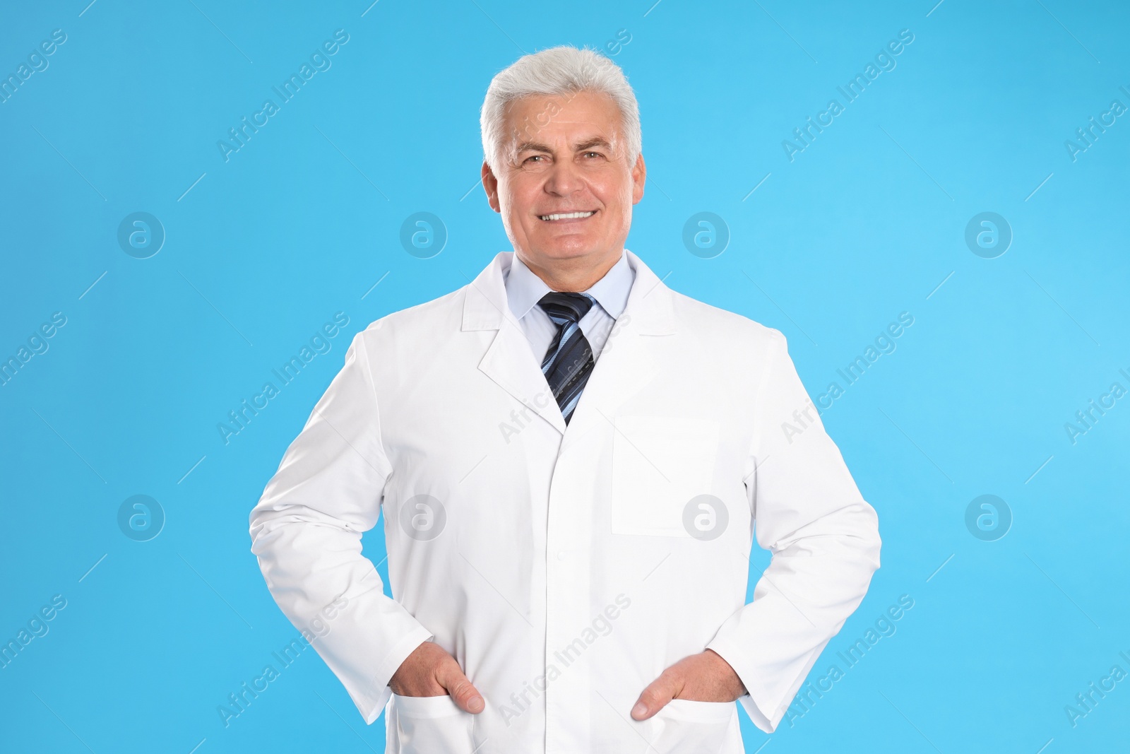 Photo of Happy senior man in lab coat on light blue background