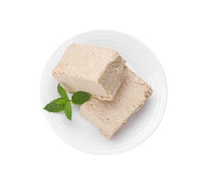 Plate with pieces of tasty halva and mint isolated on white, top view