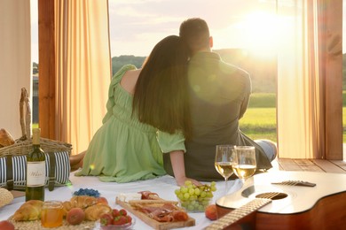Photo of Romantic date. Couple spending time together during picnic on sunny day, back view