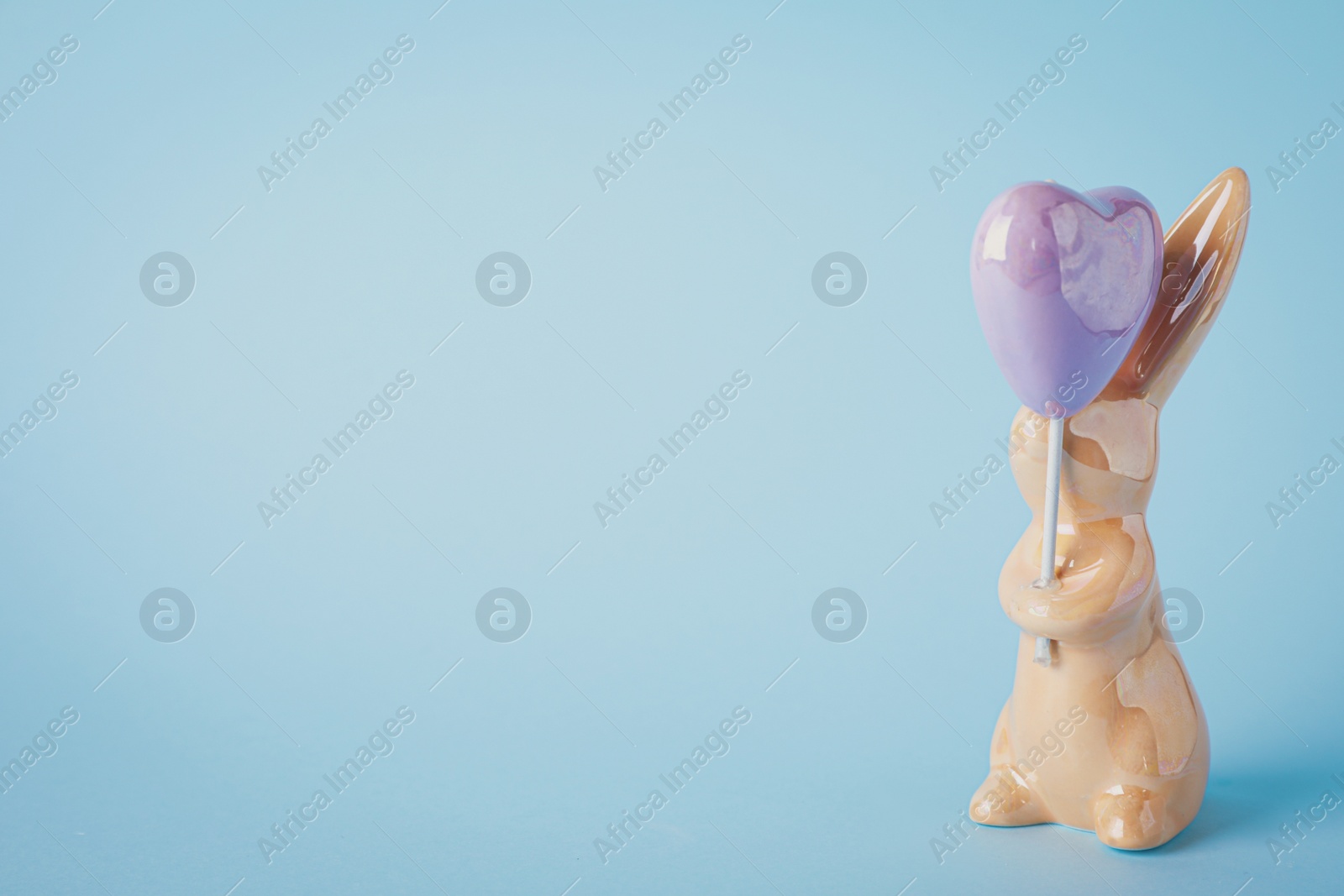 Photo of Bunny ceramic figure as Easter decor on blue background. Space for text