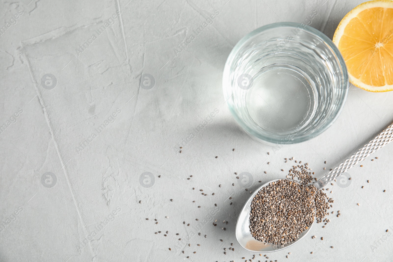 Photo of Spoon with chia seeds and glass of water on grey background, flat lay. Space for text