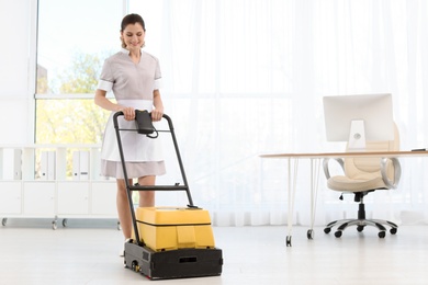 Photo of Female worker with floor cleaning machine indoors