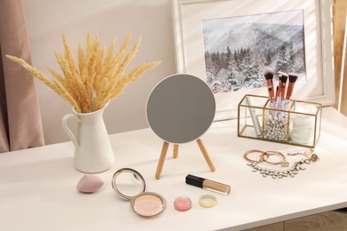 Dressing table with mirror, cosmetic products and jewelry in makeup room