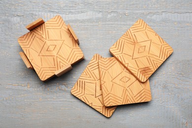 Photo of Stylish cup coasters and holder on grey wooden table, flat lay