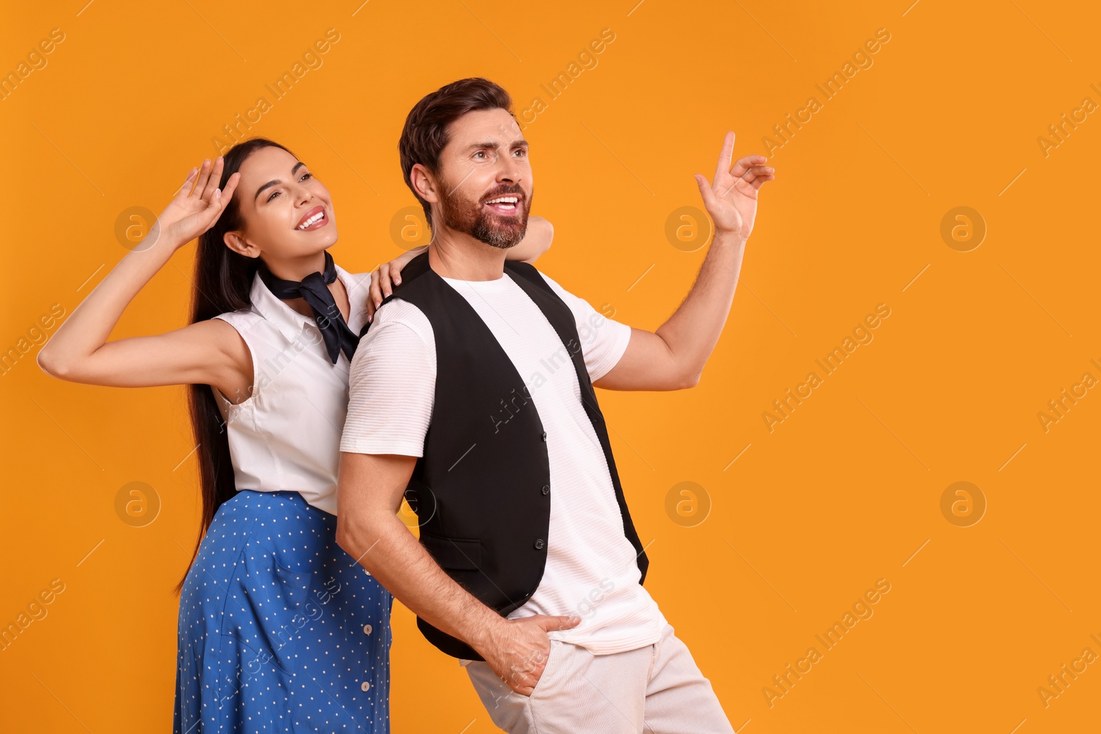 Photo of Happy couple dancing together on orange background, space for text