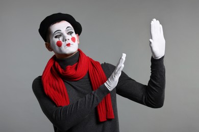 Mime artist in beret posing on grey background