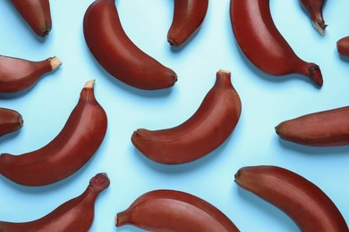 Tasty red baby bananas on light blue background, flat lay