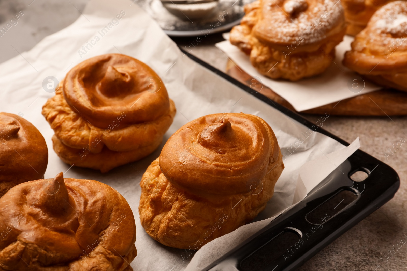 Photo of Freshly baked delicious profiteroles on grey table, closeup