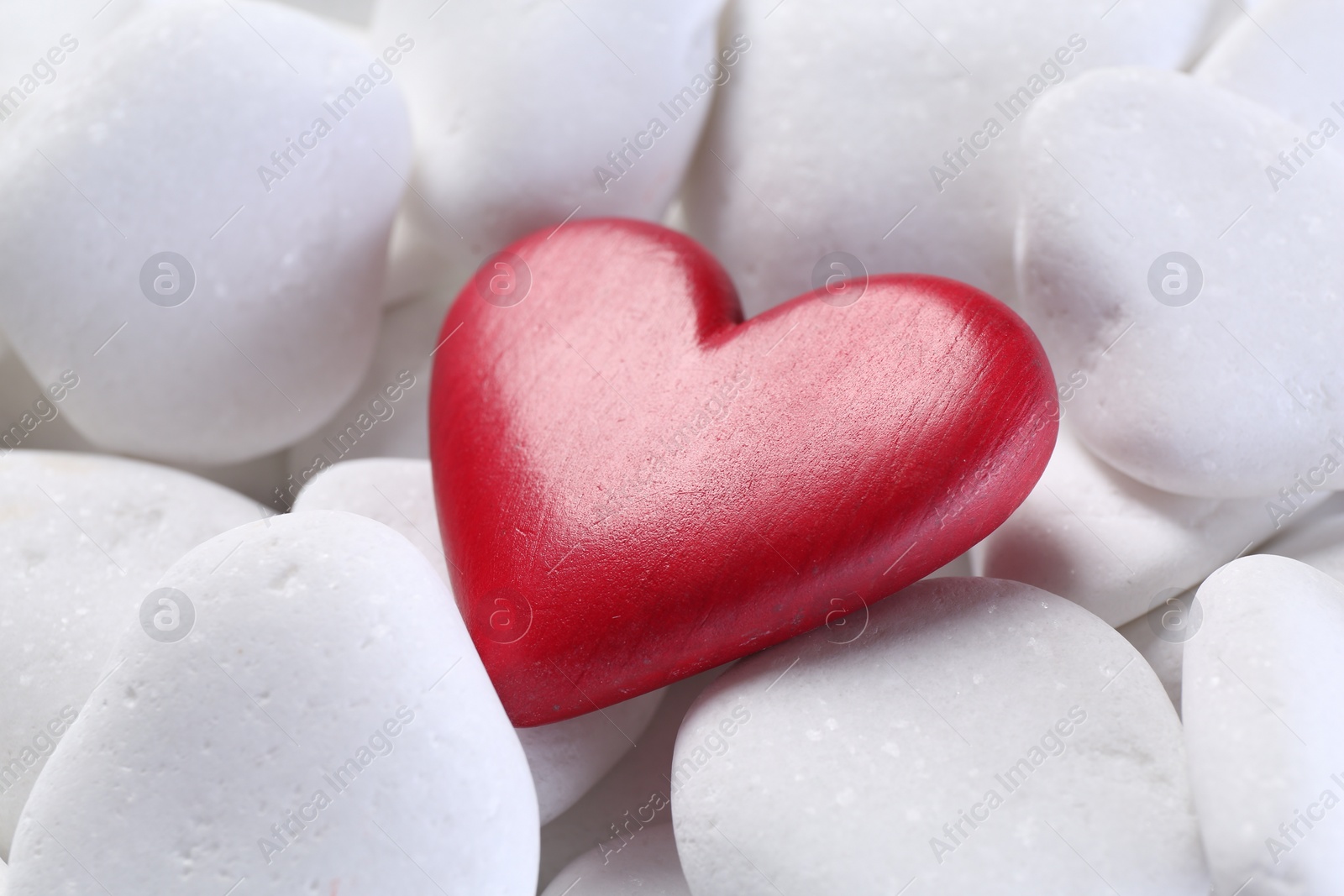 Photo of Decorative heart on white pebble stones, closeup