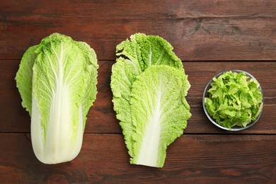 Photo of Whole and cut fresh Chinese cabbage on wooden table, top view