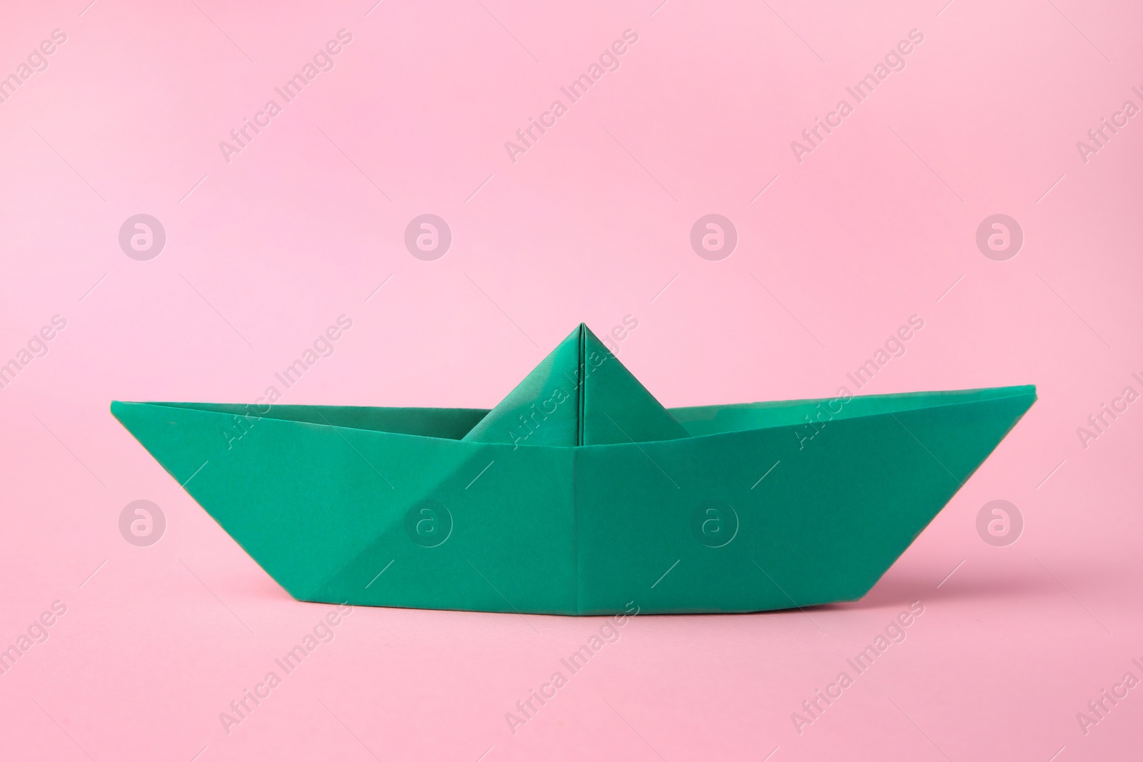 Photo of Origami art. Paper boat on pink background