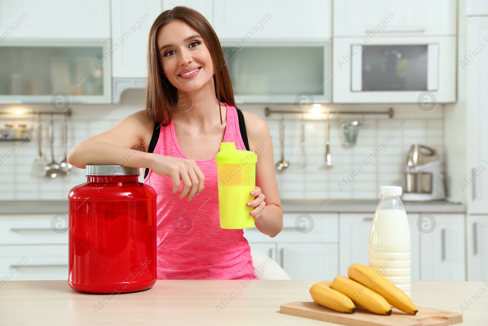 Photo of Young woman with bottle of protein shake in kitchen