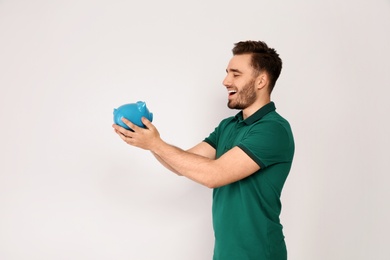 Photo of Young man with piggy bank on light background